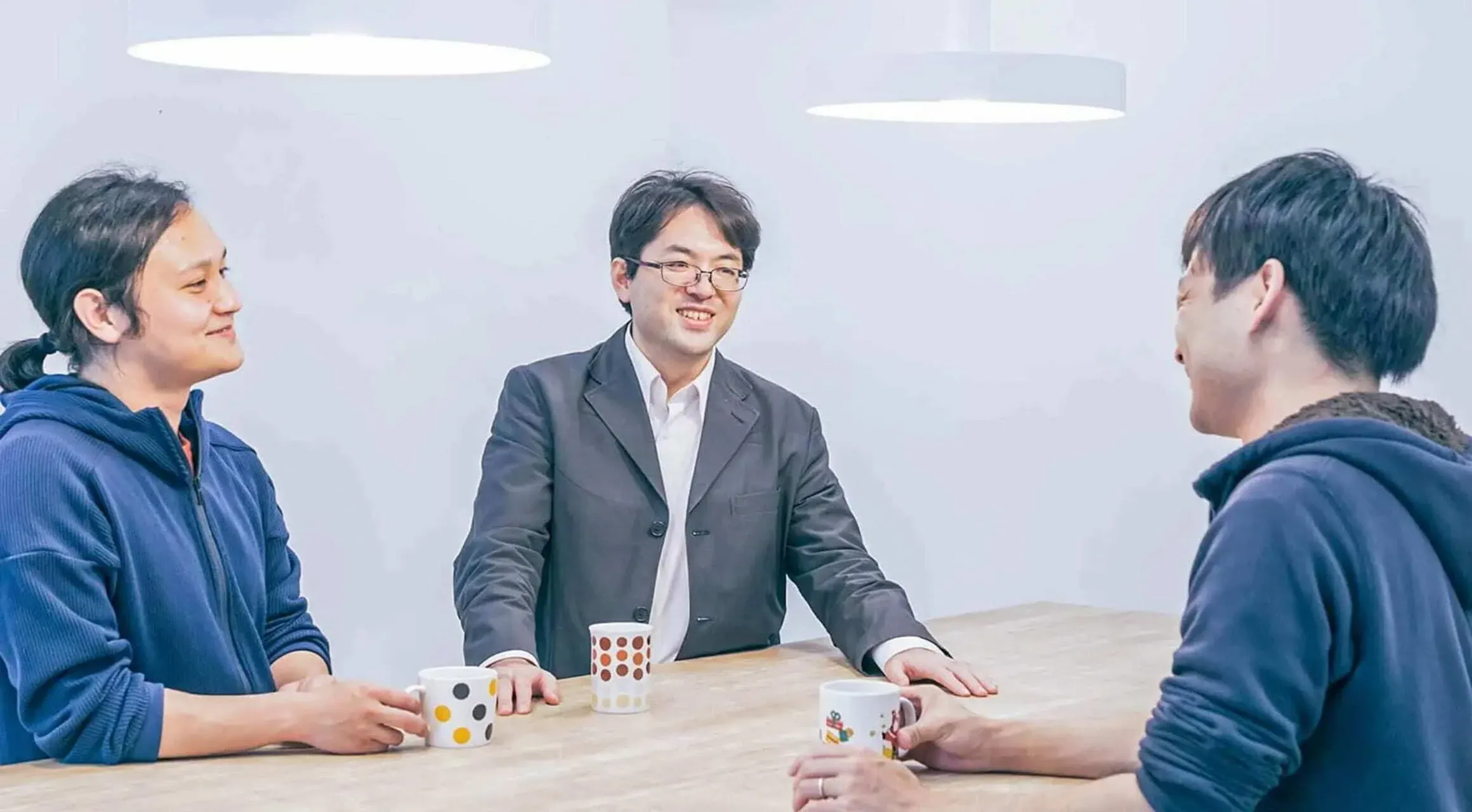 オフィスで笑顔で談笑する3人のエンジニアたち