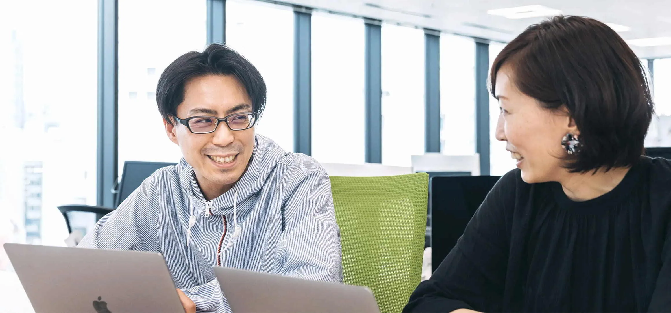 オフィスで談笑しながら仕事をする営業メンバー