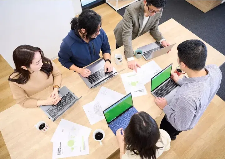 5人のチームメンバーがテーブルを囲んで協力して作業している様子