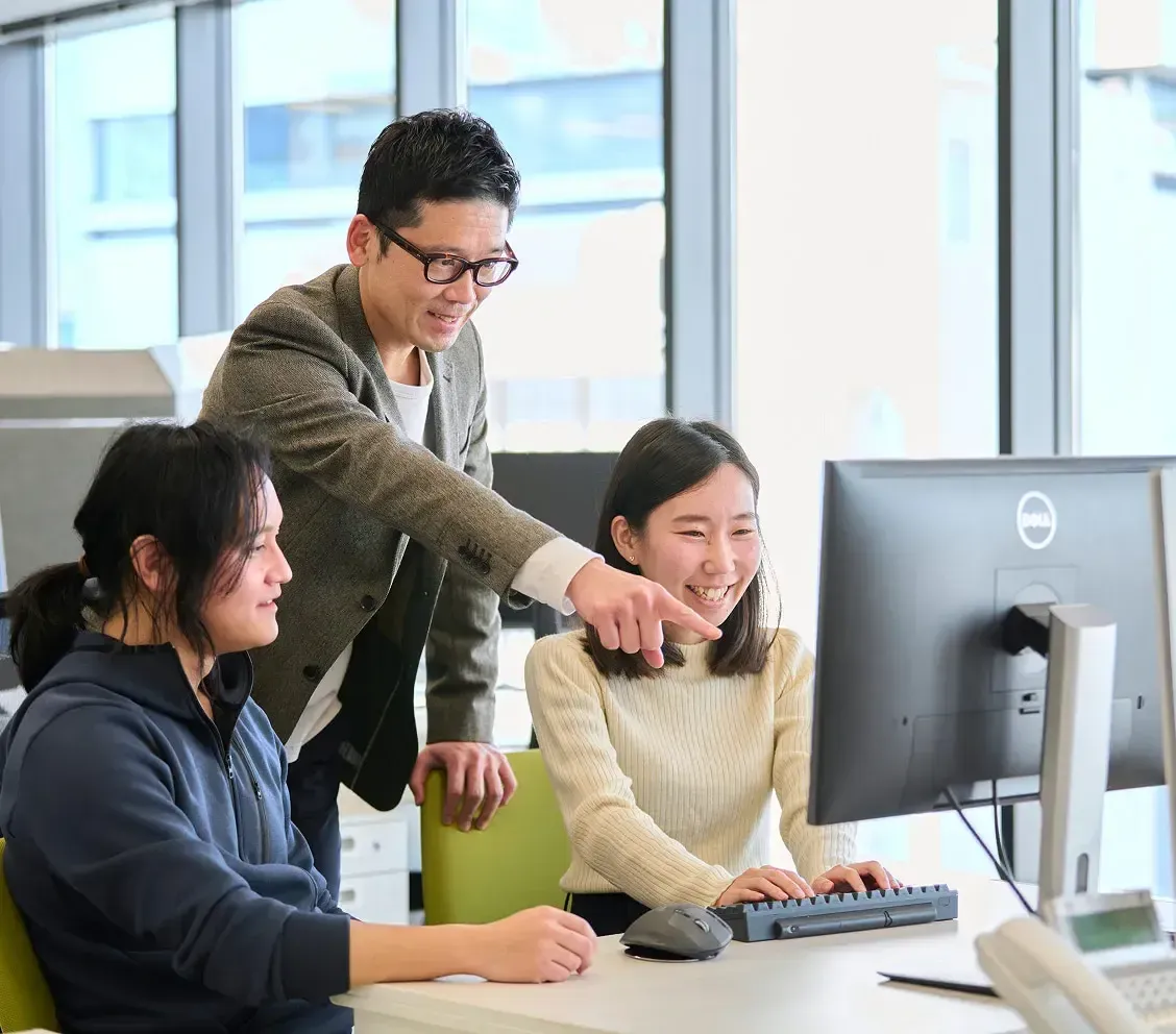 3人のチームメンバーがオフィスで協力して作業している様子