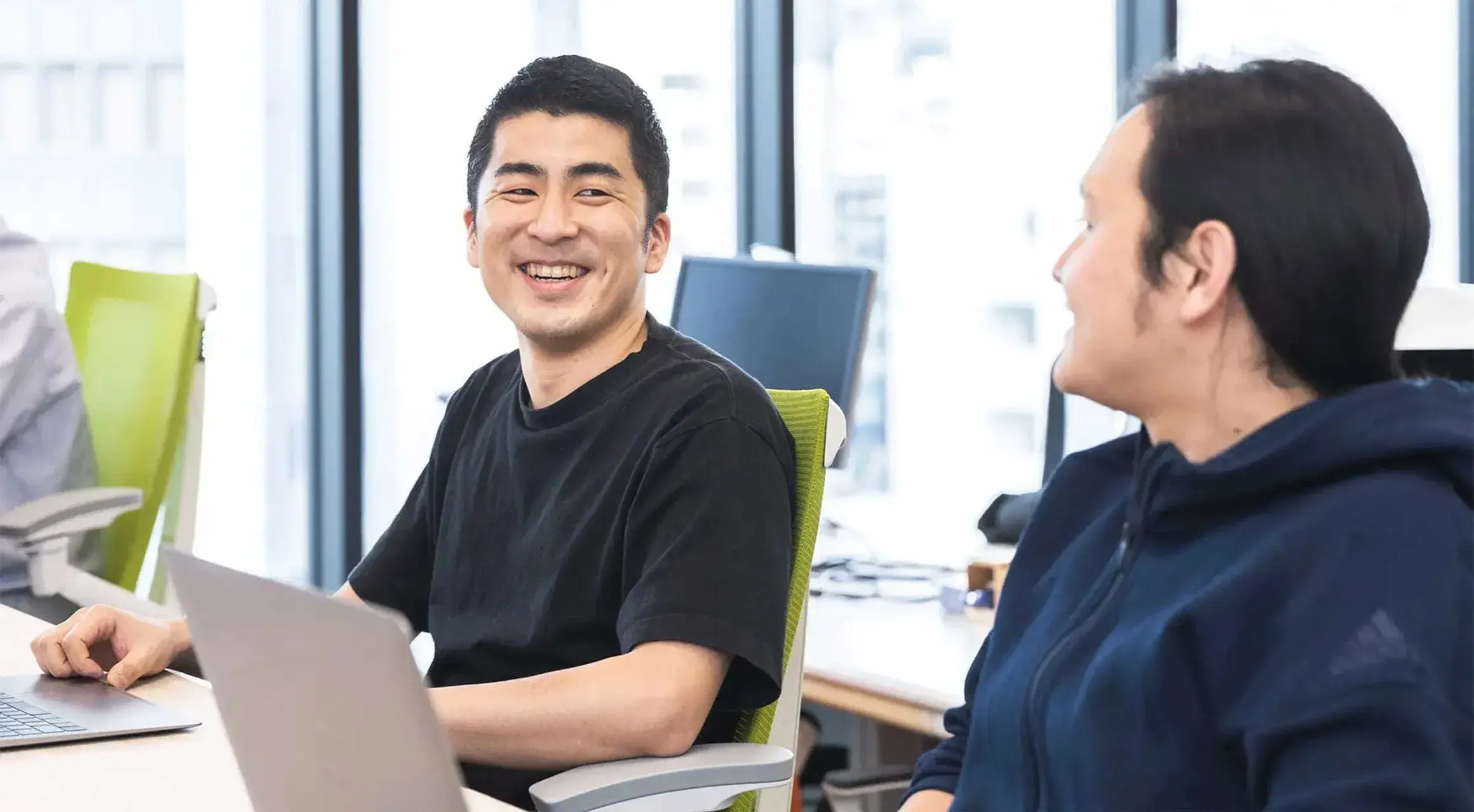 オフィスで談笑する営業チームのメンバー