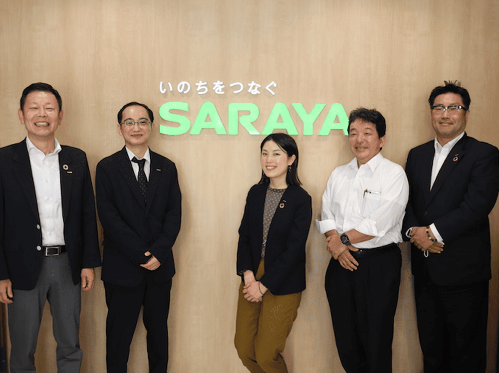 サラヤ株式会社 情報システム本部 取締役本部長 桧垣一彦様（左） 情報システム本部 係長 坪田朋之様（中左） コミュニケーション本部 CX部 部長 新川隆弘様（中右） コミュニケーション本部 CX部 主任 森英樹様（右） コミュニケーション本部 広報宣伝統括部 兼 コンシューマー事業本部 プロモーション部 係長 服部蛍様（中央）